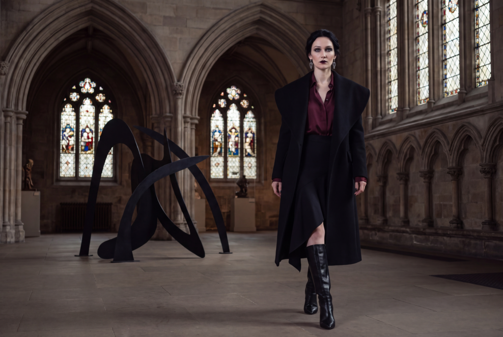 Marishka Vespera wearing modern Gothic tailoring in a Gothic Revival gallery.